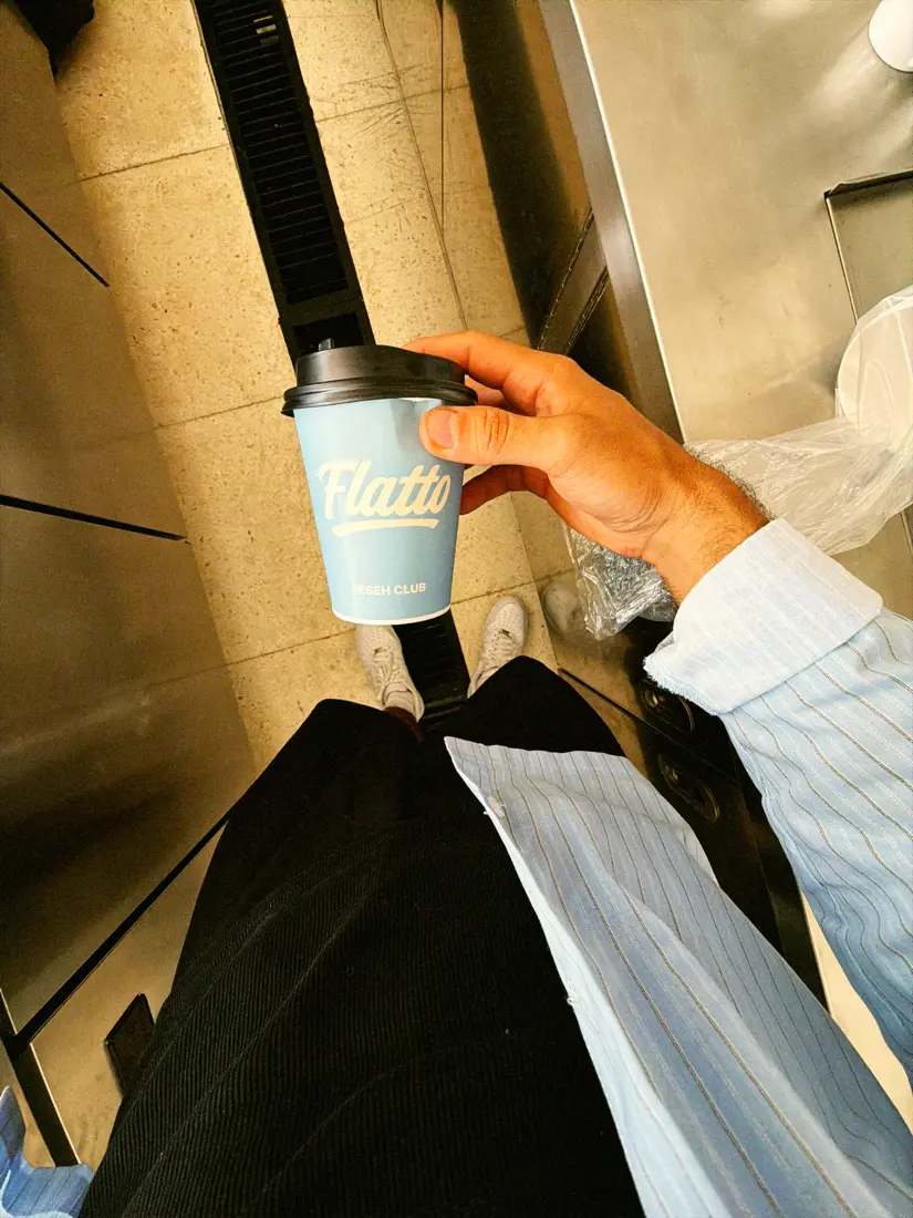 A pale blue Flatto Seseh Club takeaway cup held in one hand